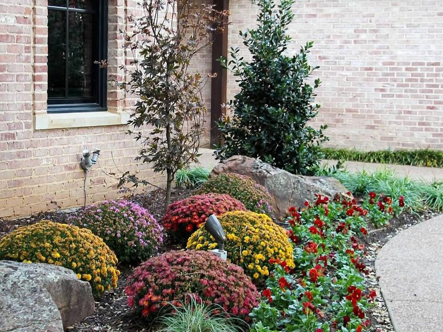Colorful seasonal flower beds with ornamental grasses and boulders