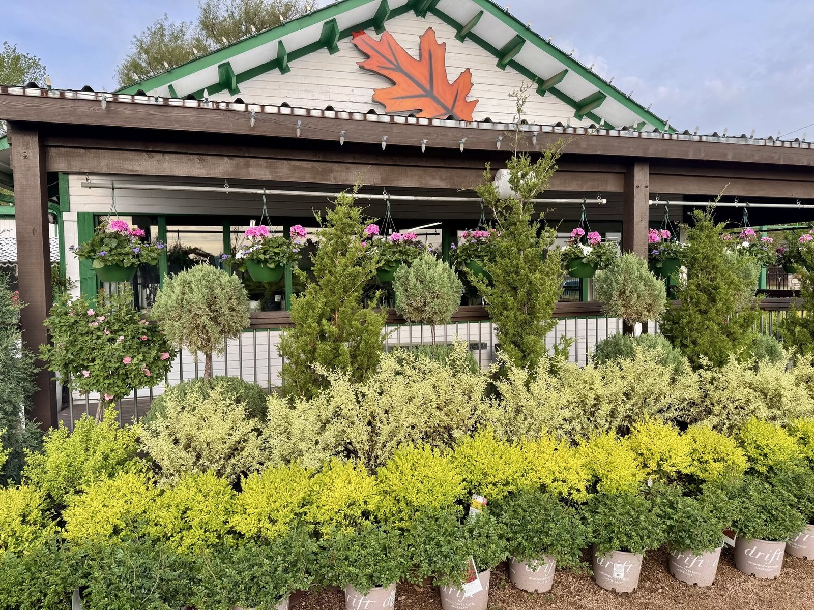 The Land Care Garden Center storefront in Flower Mound, TX, with its orange oak leaf sign and rows of plants